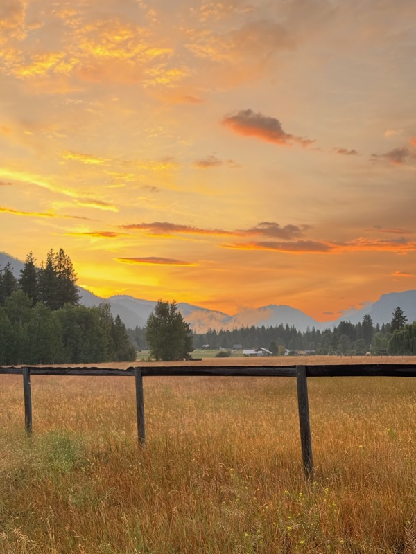 Fiery orange sunset over the pasture and wooden fence