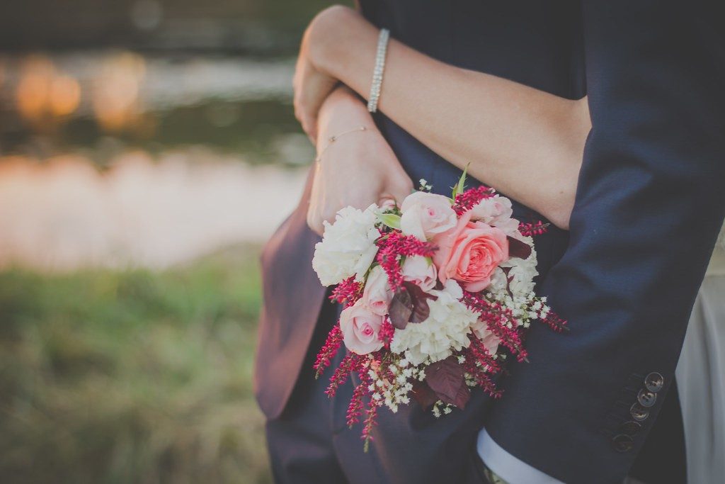 A couple embracing at golden hour, the bride holding a pink rose bouquet